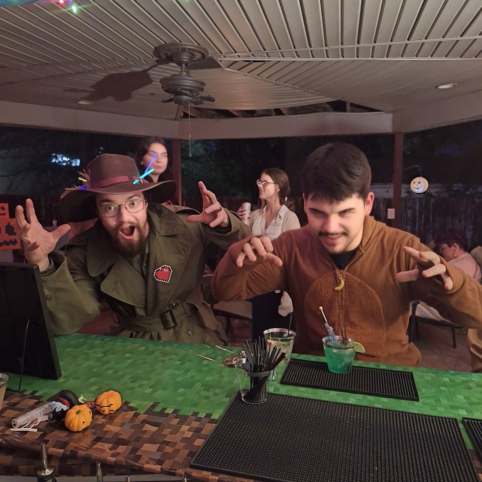 Two guests in halloween costumes posing at the full bar with drinks