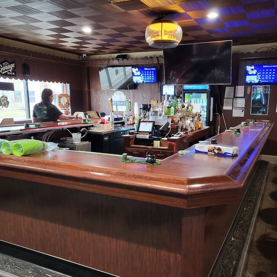Interior of Village Tavern bar with wooden counter, drinks, and TVs
