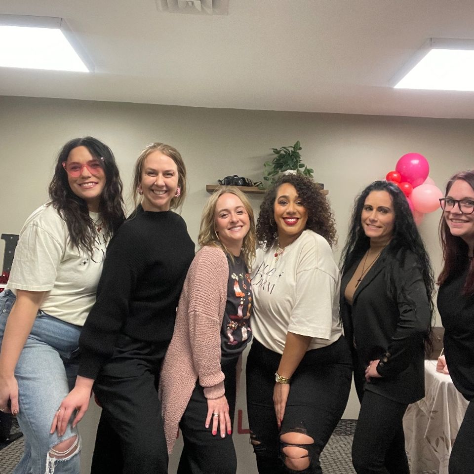 Women smiling and posing at the Valentine’s themed social event
