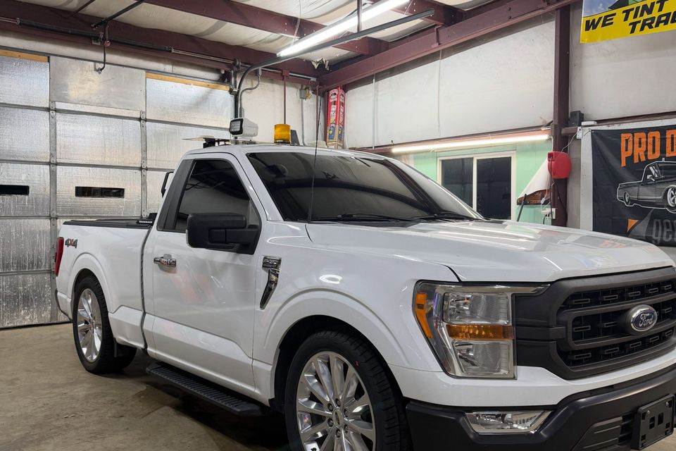 White Ford F-150 regular cab with tinted windows in a Moyock North Carolina tint shop bay