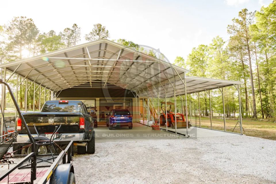 Wide steel carport sheltering trucks and cars in wooded lot with SBSI watermark representing steel carports in Alabama