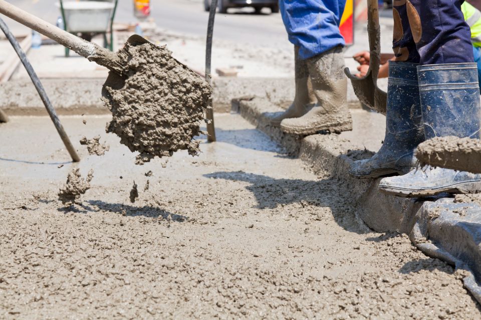 A stock image of a skilled construction crew pouring and finishing concrete on a railroad track, used in a blog by Cannone Marketing.