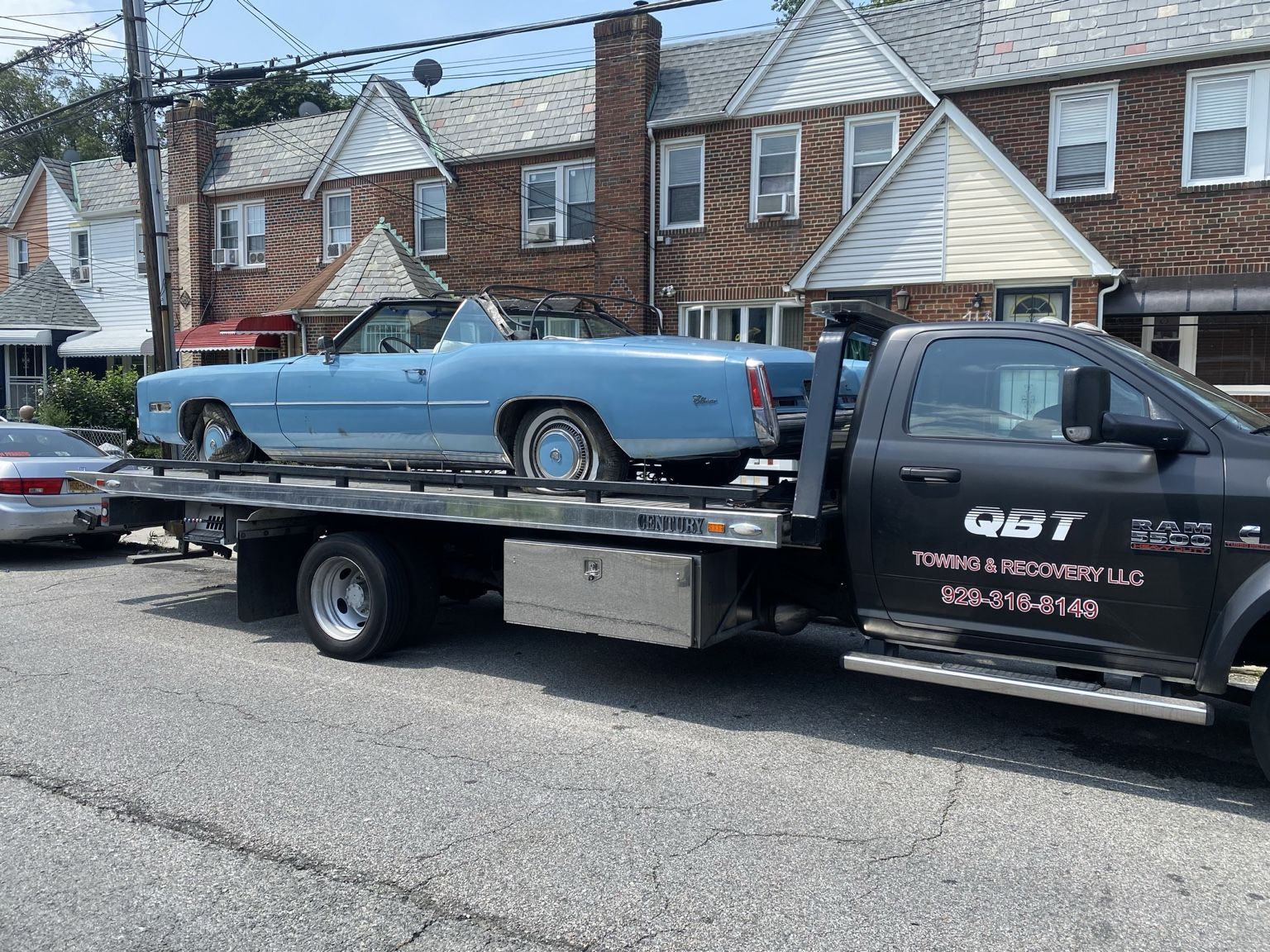 QBT flatbed loaded with a blue car
