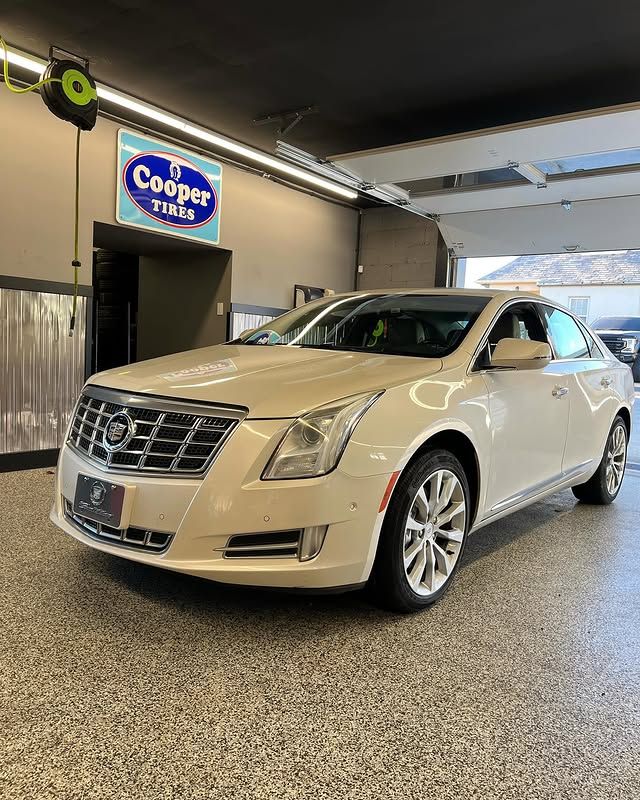 White Cadillac XTS sedan inside tire shop with Cooper Tires sign on wall in Claymont DE