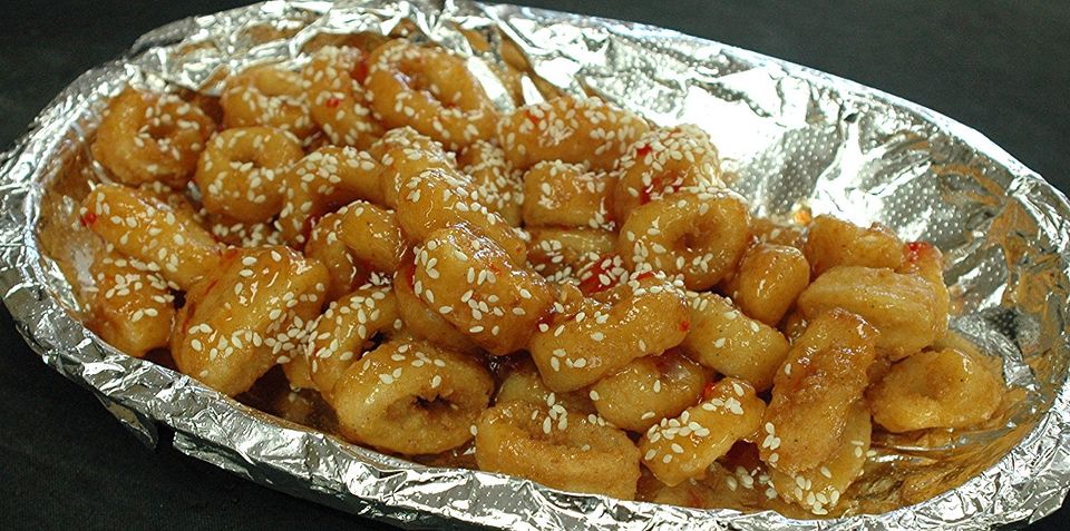 Appetizer bites coated in sauce and sprinkled with sesame seeds.