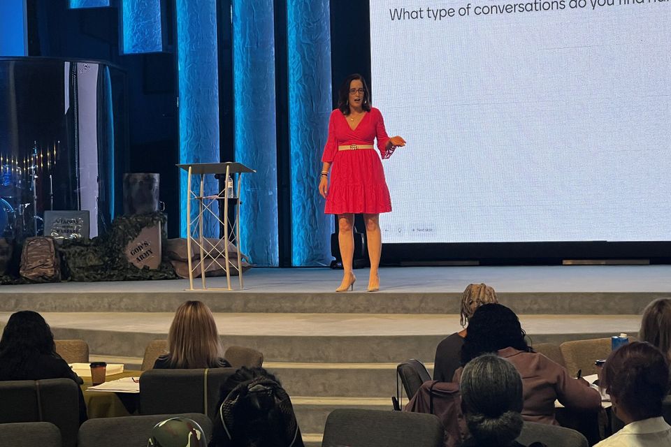 Woman standing on stage speaking to group