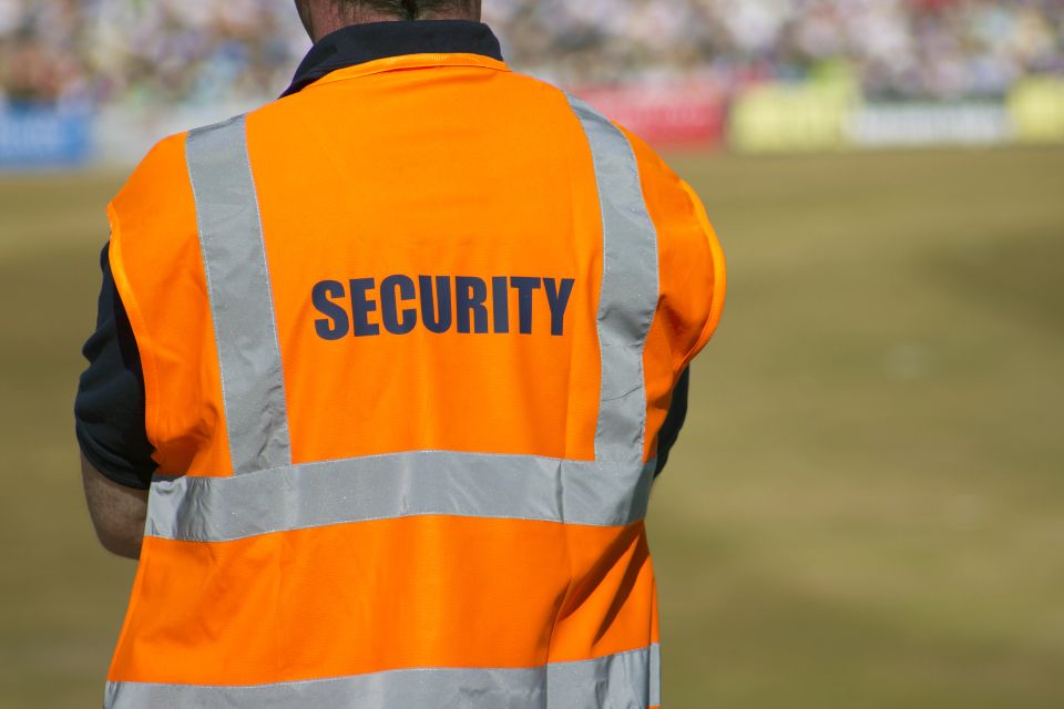 A security guard in an orange vest on his shift