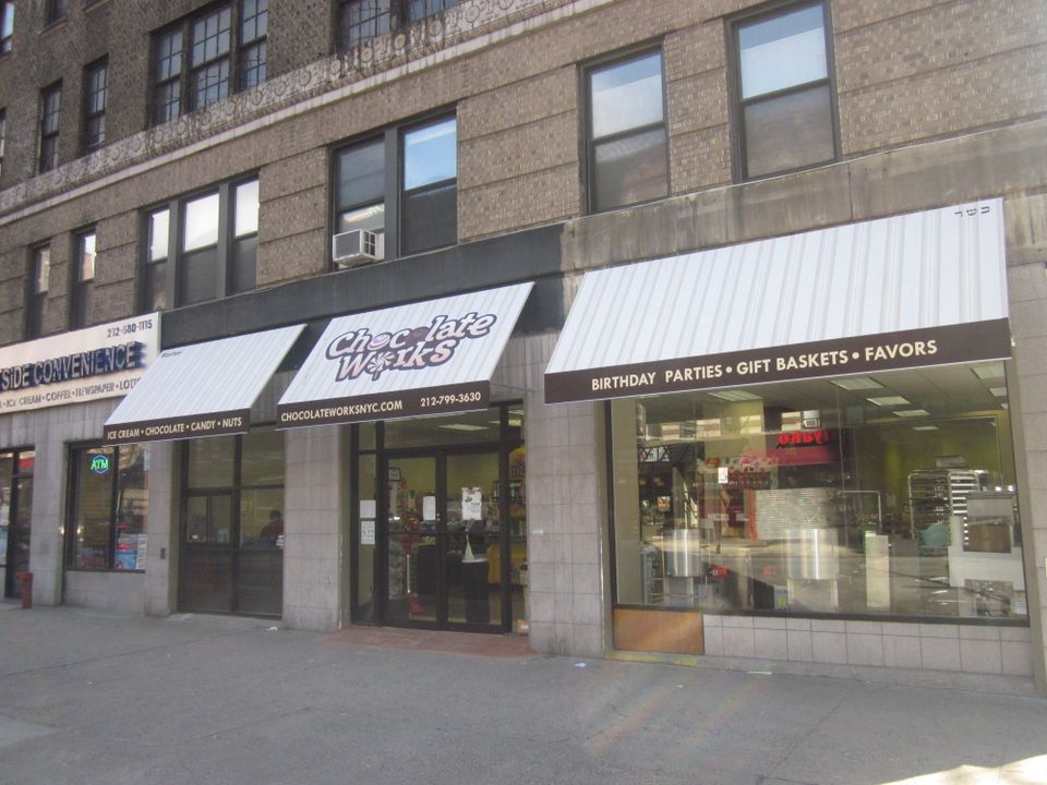 Row of cream storefront awnings with printed lettering across three adjoining retail bays on a New York City building
