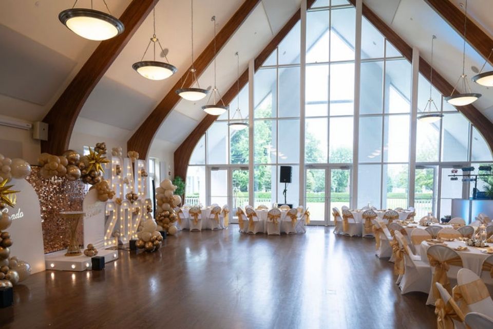 Vaulted event hall set with gold-accented tables and balloon installations for a graduation in the Hamptons NY