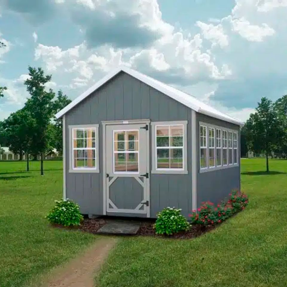 Gray gardener greenhouse shed with white trim and glass windows on a Knoxville TN lawn
