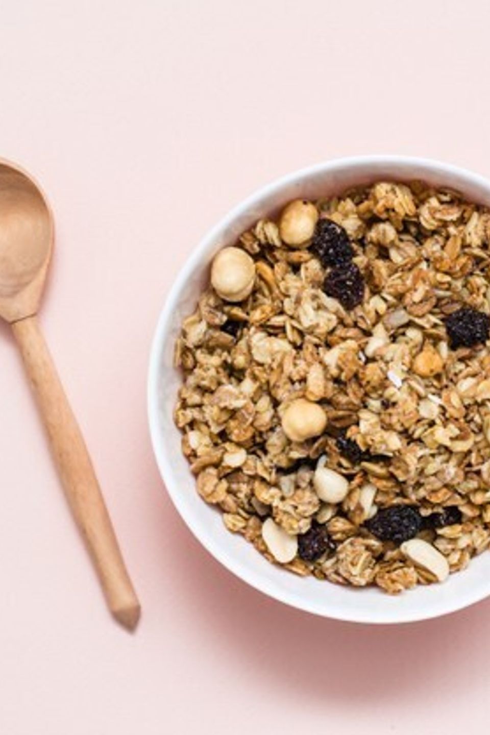 Healthy eating baked granola oats nuts raisins bowl wooden spoon pink surface top view 107288 3124