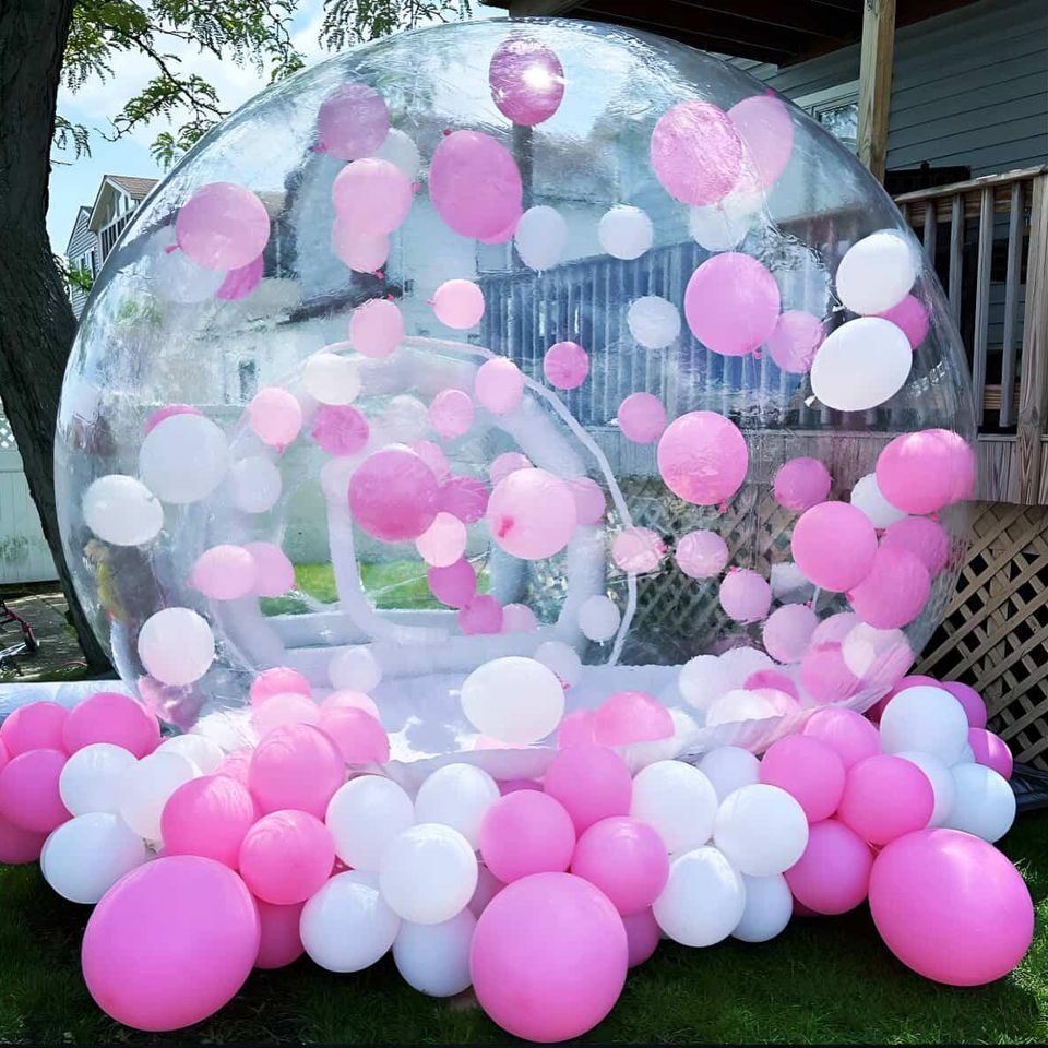 Clear bubble house filled with pink and white balloons, creating a whimsical event rental backdrop for parties and celebrations by Aldys Events