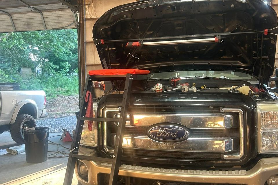 Black Ford Super Duty truck with hood open inside diesel repair service bay in Arab Alabama