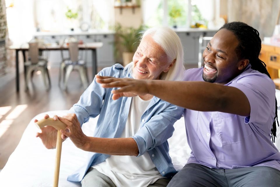 A caretaker and his senior female patient laughing and smiling