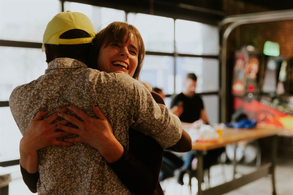 Two people hugging in front of pinball machines