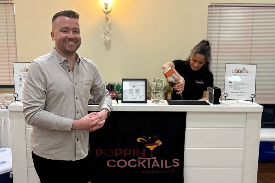 Bartender pouring a drink while a guest stands at the bar during an event