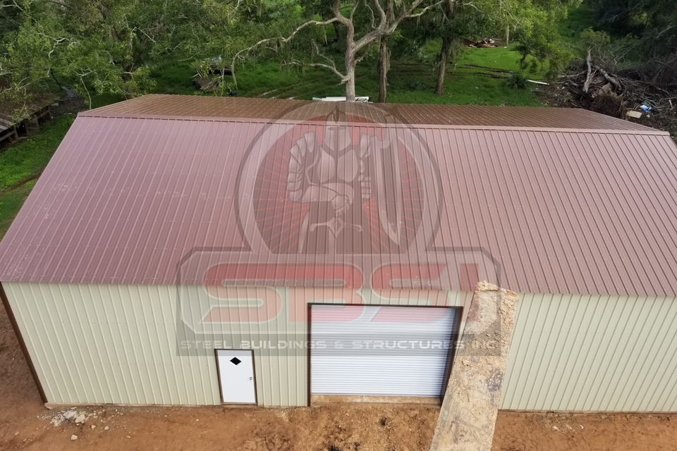 Aerial view of steel building with red roof and roll up door with SBSI watermark representing steel buildings in Alabama
