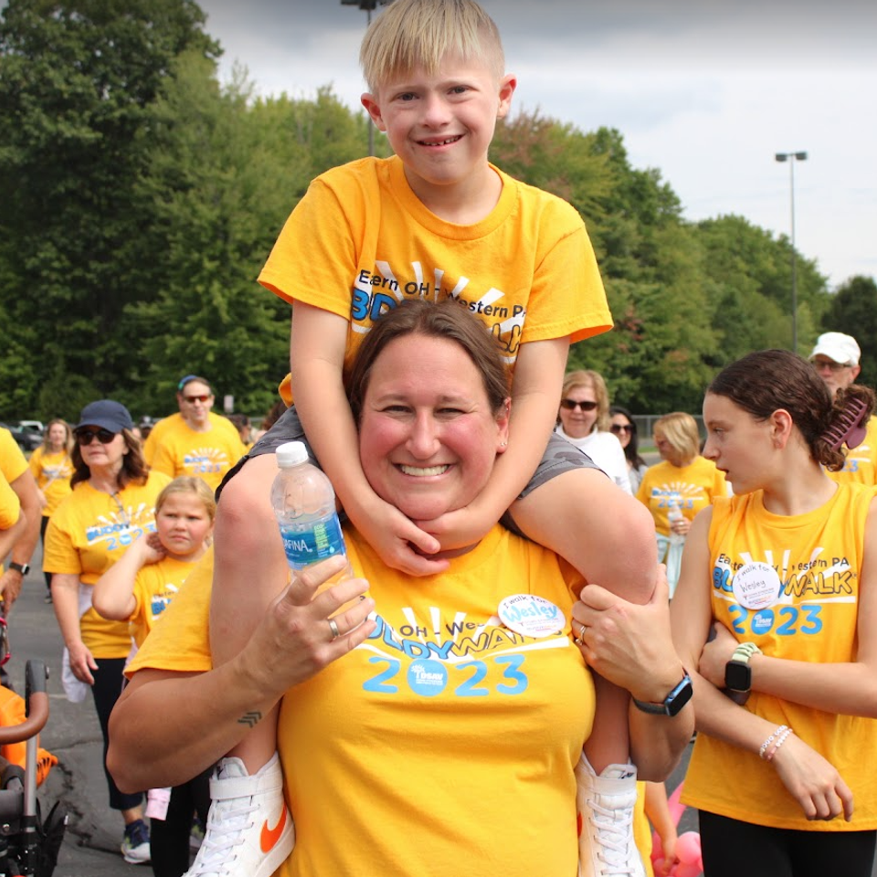 Child riding on an adult's shoulders during the Down Syndrome Association of the Valley Buddy Walk.