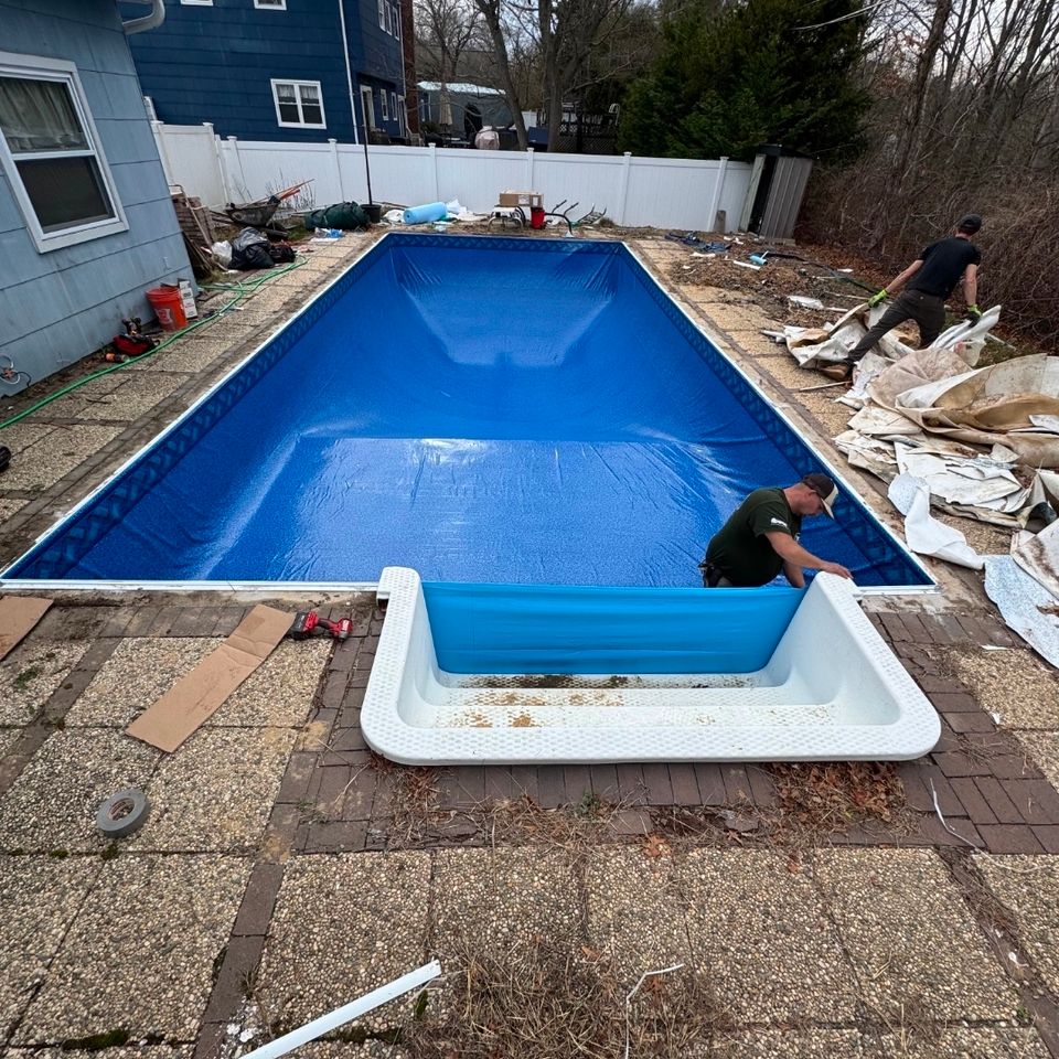 Crew fitting a new vinyl liner in a rectangular inground pool with the step unit removed