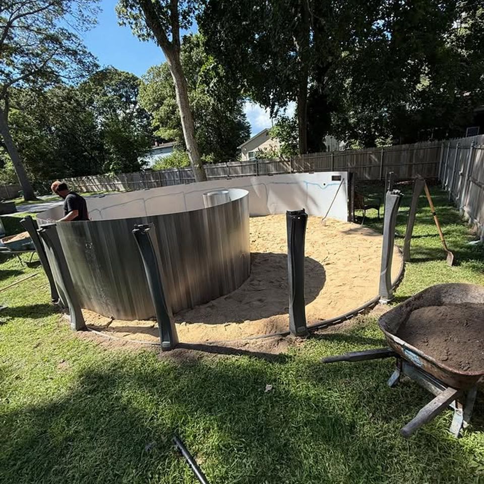 Above ground pool wall being assembled over a leveled sand base in a Long Island NY backyard