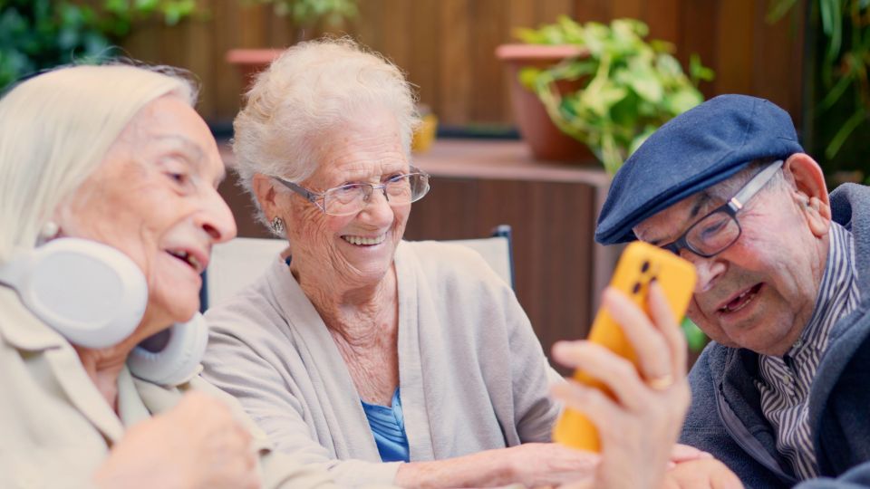3 elderly people looking on a cellphone