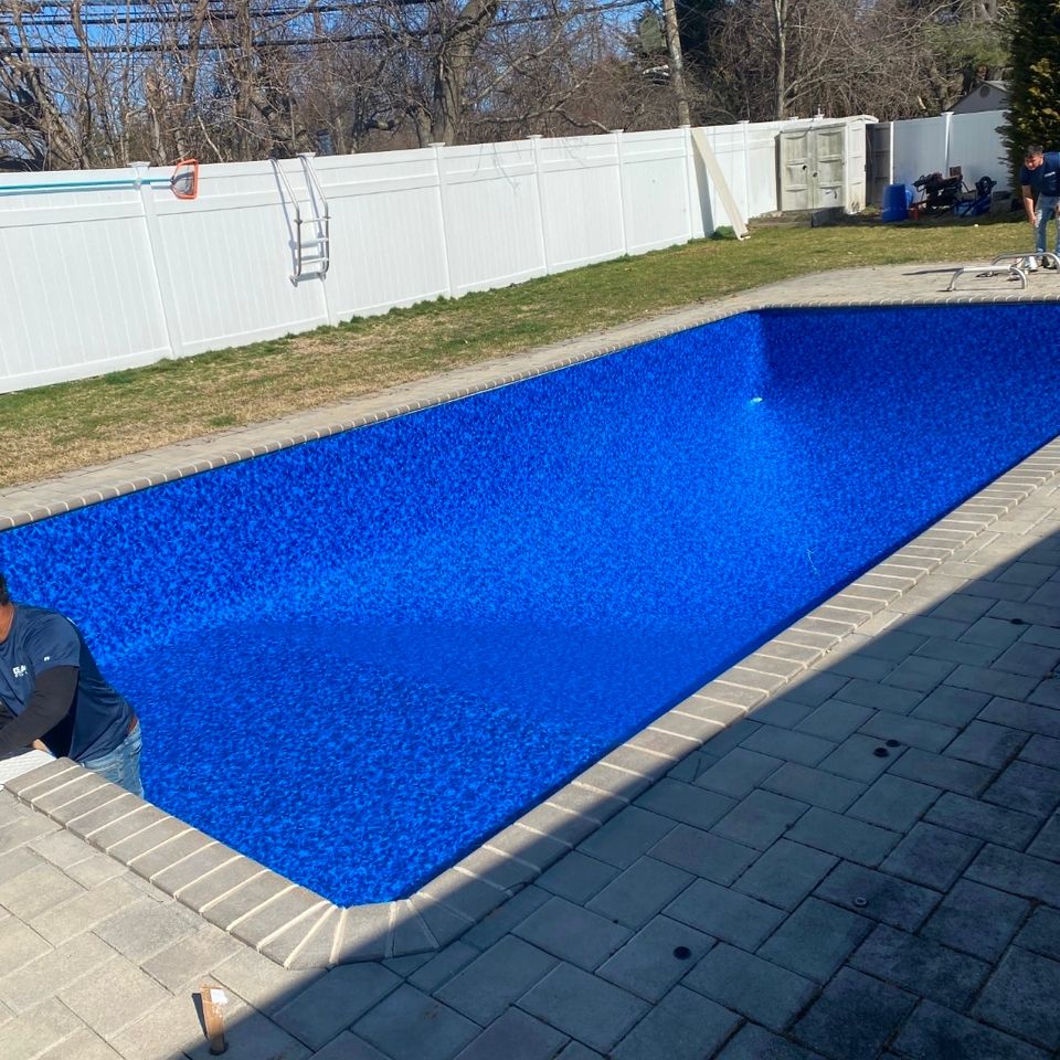 New blue vinyl liner installed in a rectangular inground pool with paver patio on Long Island