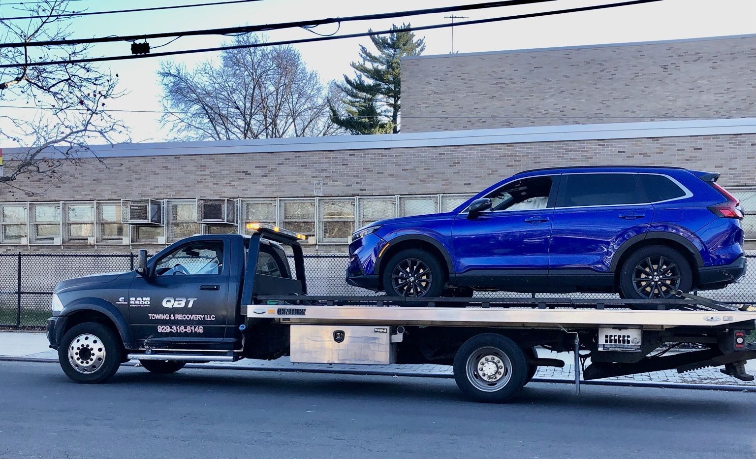 QBT flatbed transporting a blue SUV