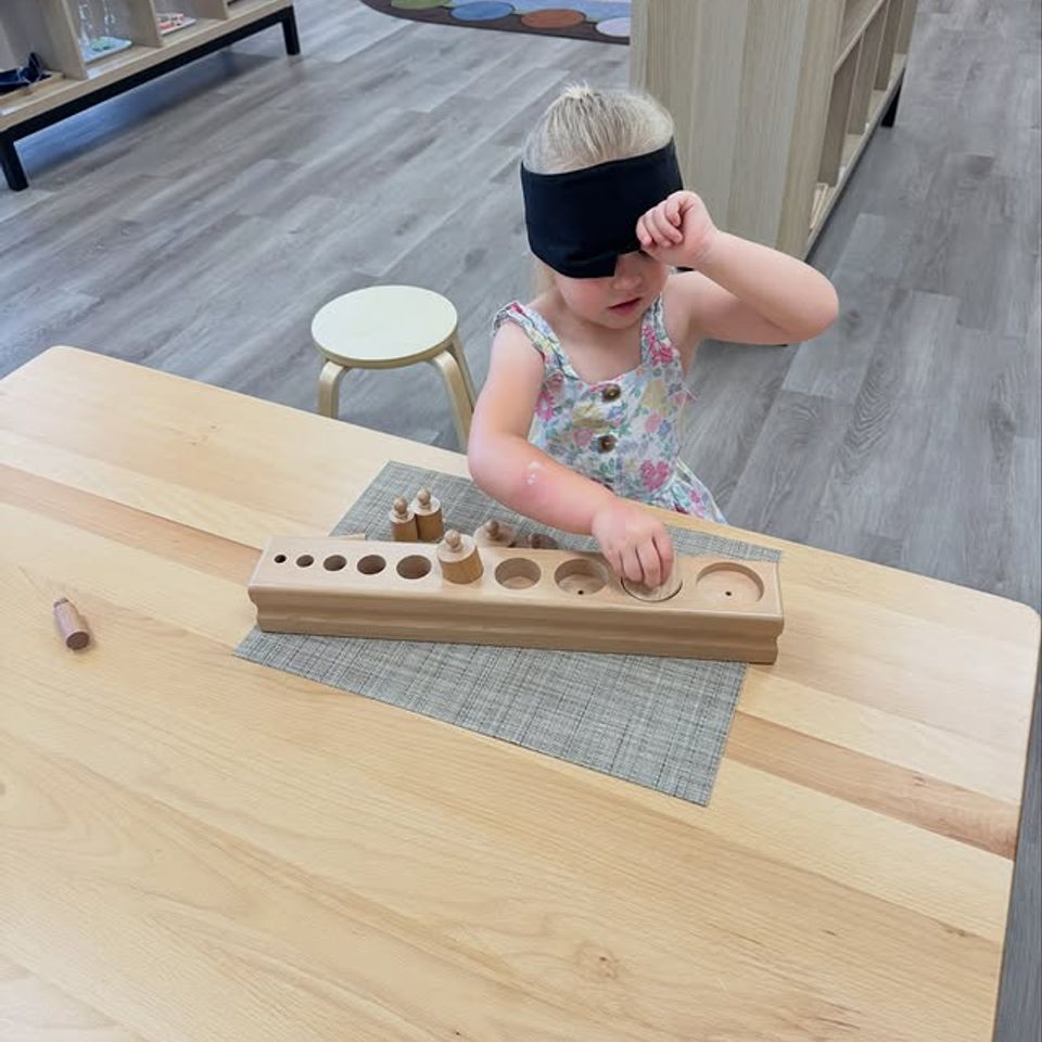 Preschool girl matching wooden cylinder blocks during a Montessori sensorial lesson in Palmdale CA