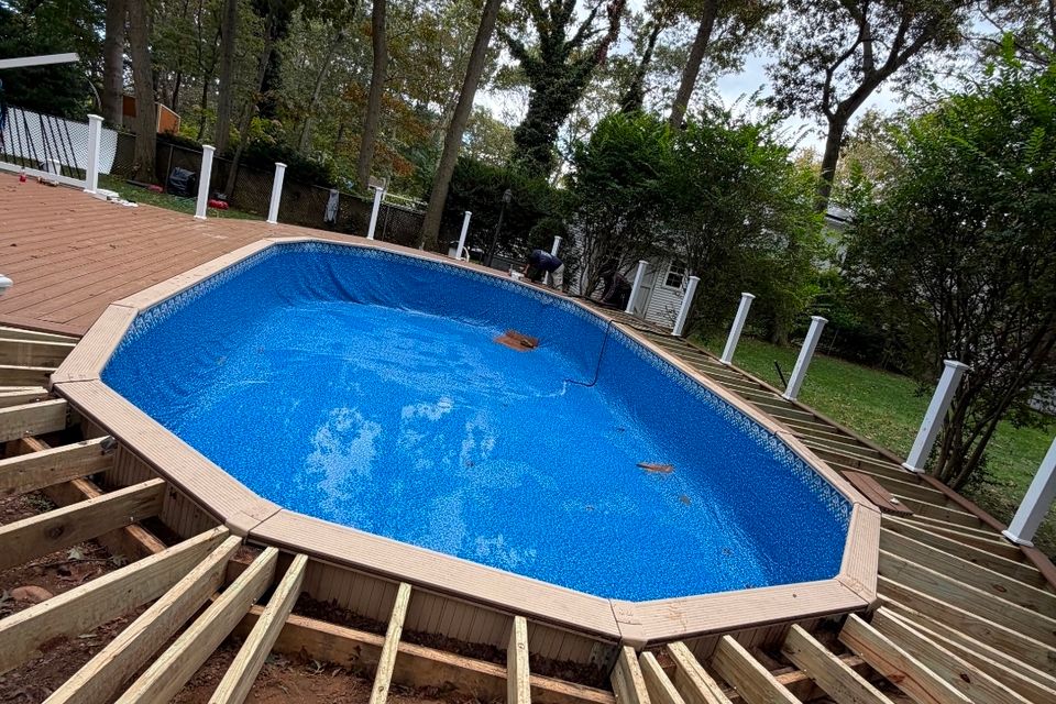 Oval above ground pool with new liner surrounded by a wood deck under construction