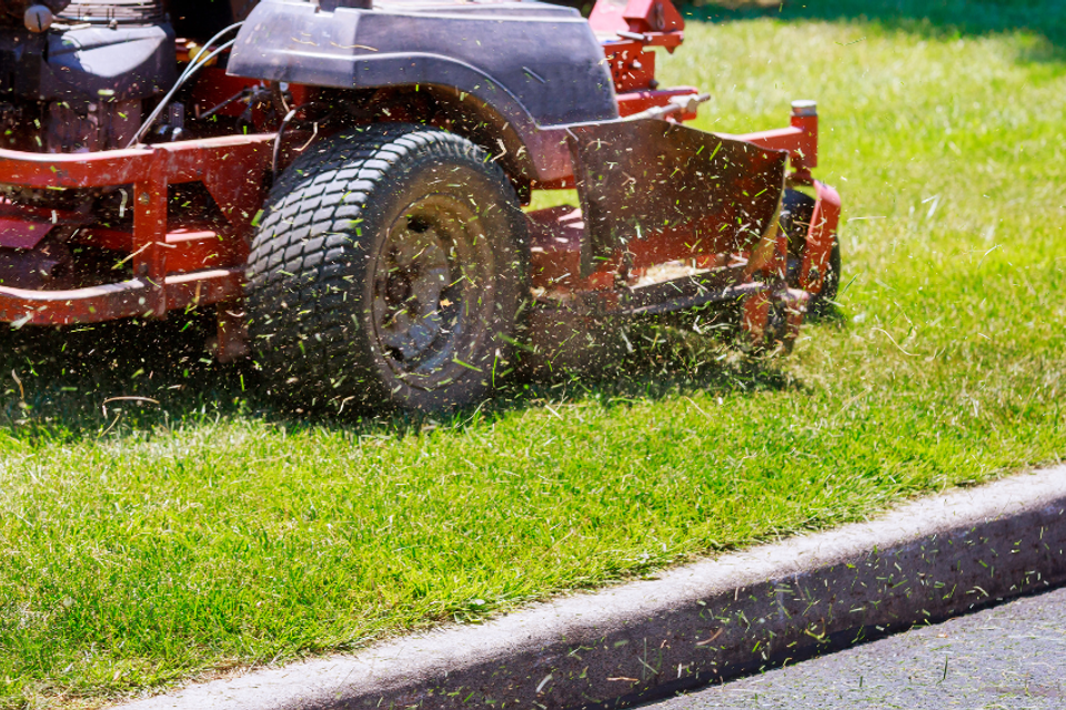 Commercial lawn mower cutting healthy green grass as part of professional lawn maintenance services by R.E.P. Companies.