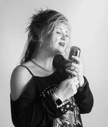 Stacy Wynette singing into a vintage microphone in a black-and-white portrait