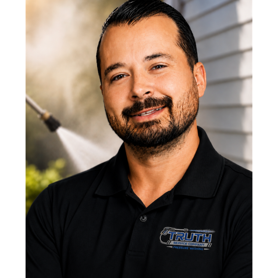 Portrait of Ron Hinderliter Jr., founder of The Truth Service Company, wearing a company polo shirt with a pressure washing scene in the background.