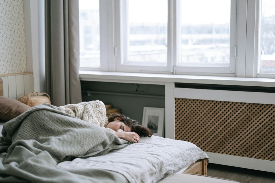 Woman laying in her bed, symbolizing the morning-after effects of a hangover.