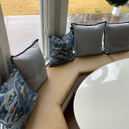 Residential leather bench under windows with pillows