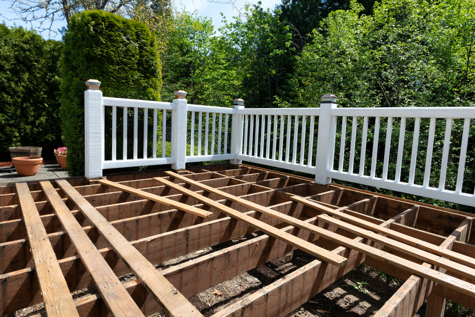 Deck under construction featuring a wood framing system and white railing for a custom outdoor living space.