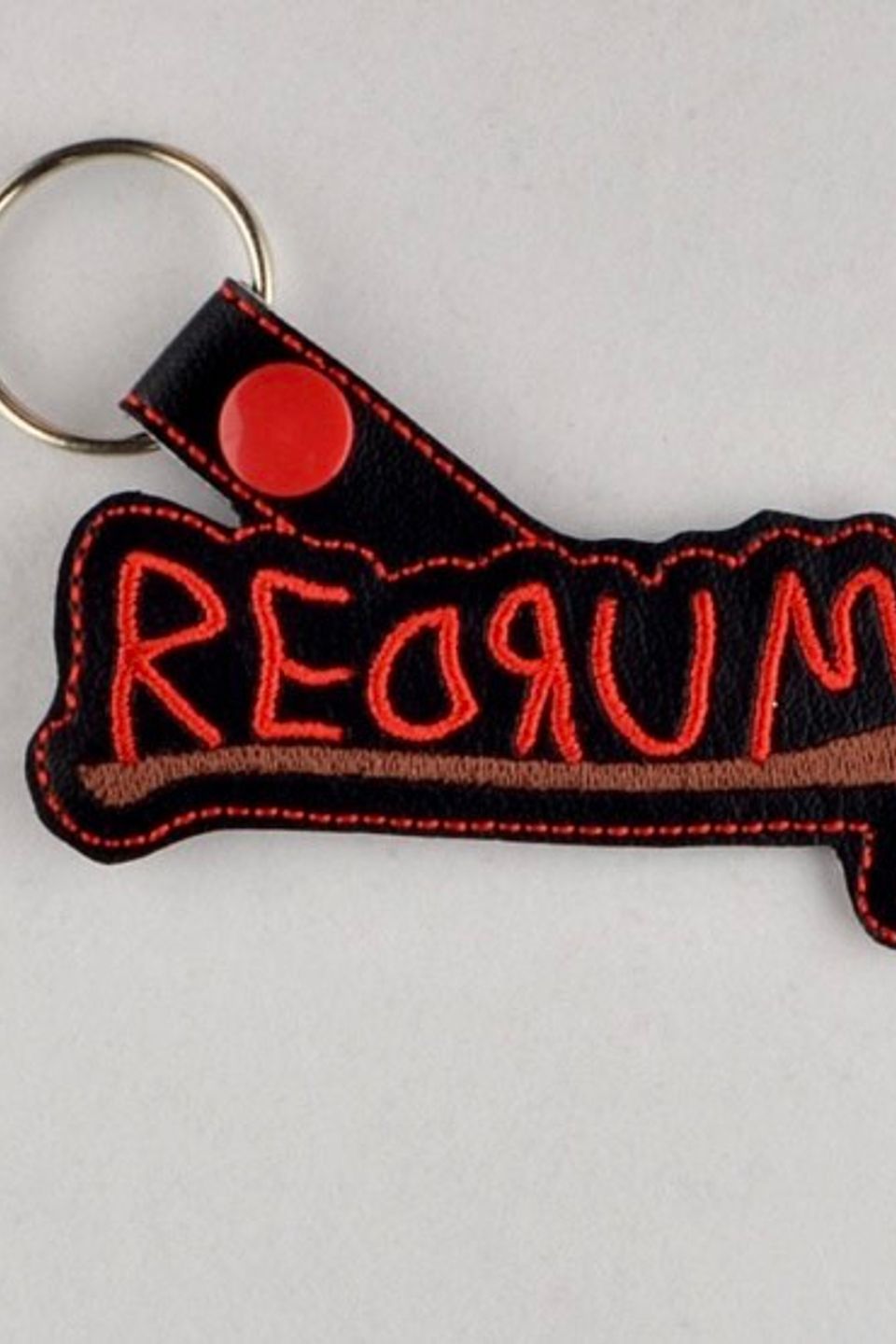 Custom embroidered REDRUM keychain with red lettering and an axe graphic inspired by classic horror films.