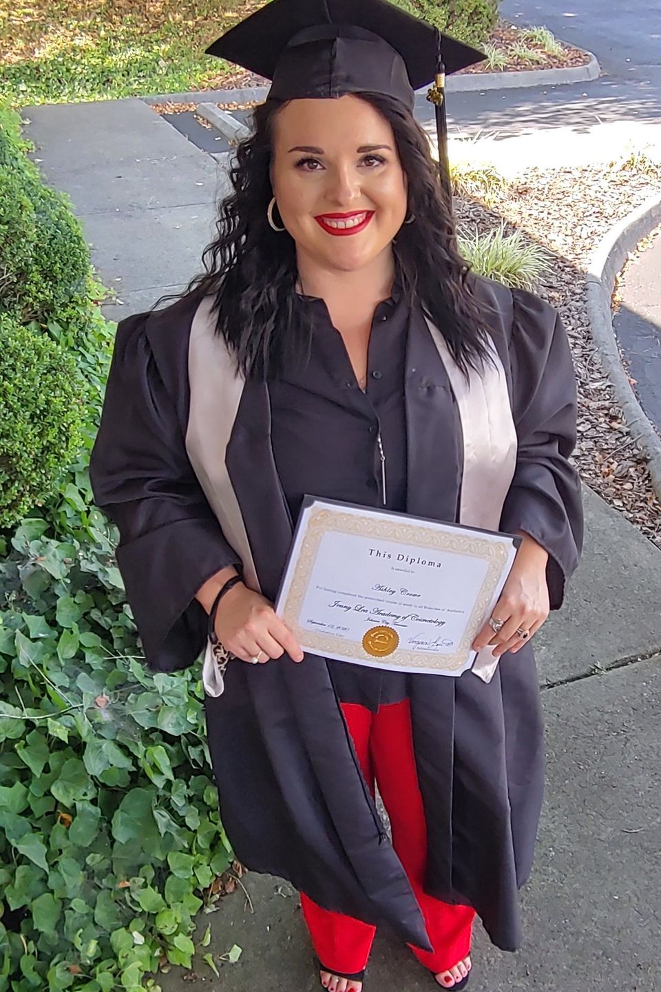 Beauty school graduate holding certificate at Jenny Lea Academy