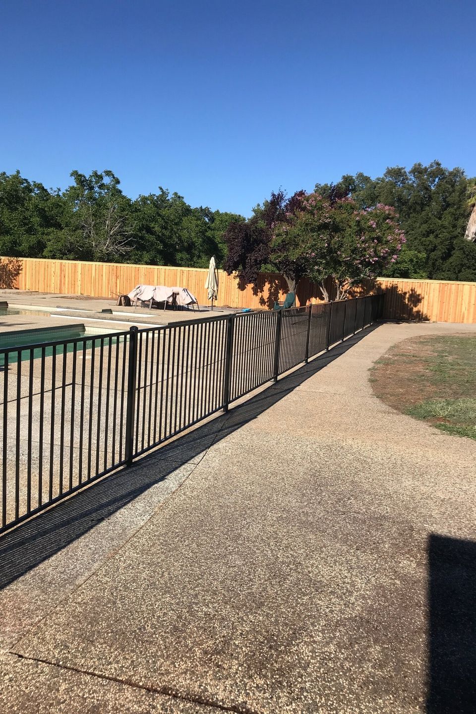 Black metal pool safety fence installed around residential swimming pool