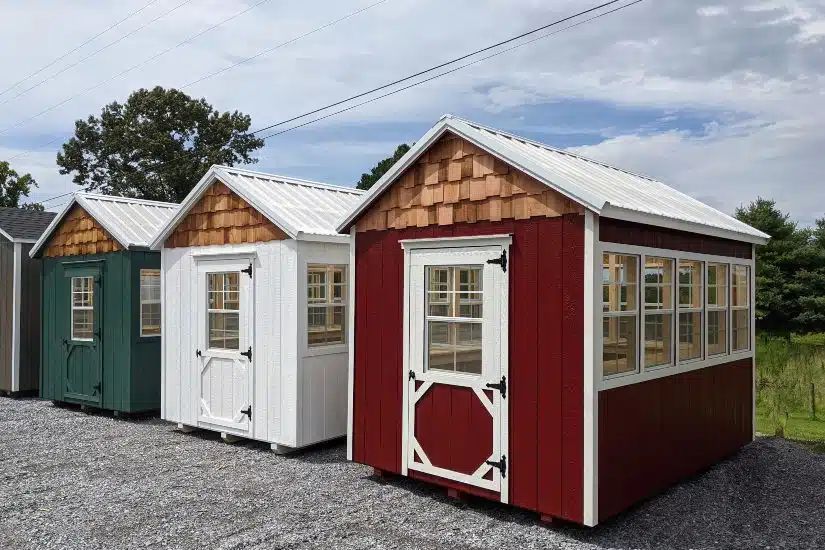 Row of red, white and green gardener greenhouses with cedar shake gables on a Knoxville TN lot