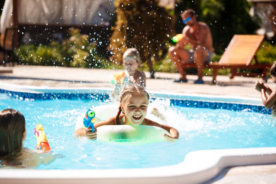 Children playing with water guns in a swimming pool
