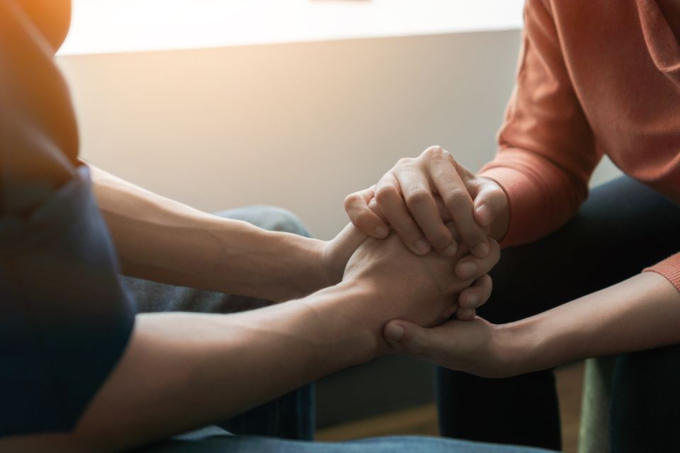 Close up of two people holding hands in a supportive gesture  representing trust  consent  and affirming sexual health care.