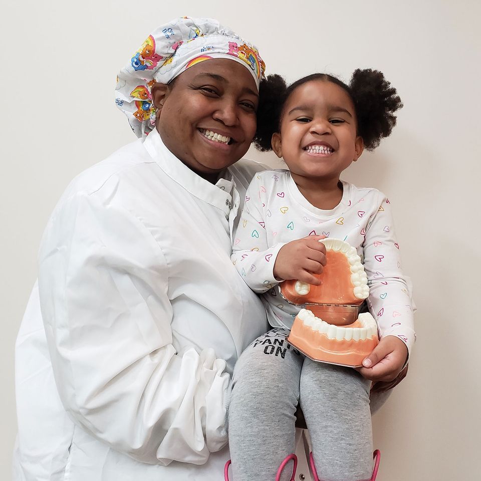 Pediatric dentist holding young patient in a friendly dental office