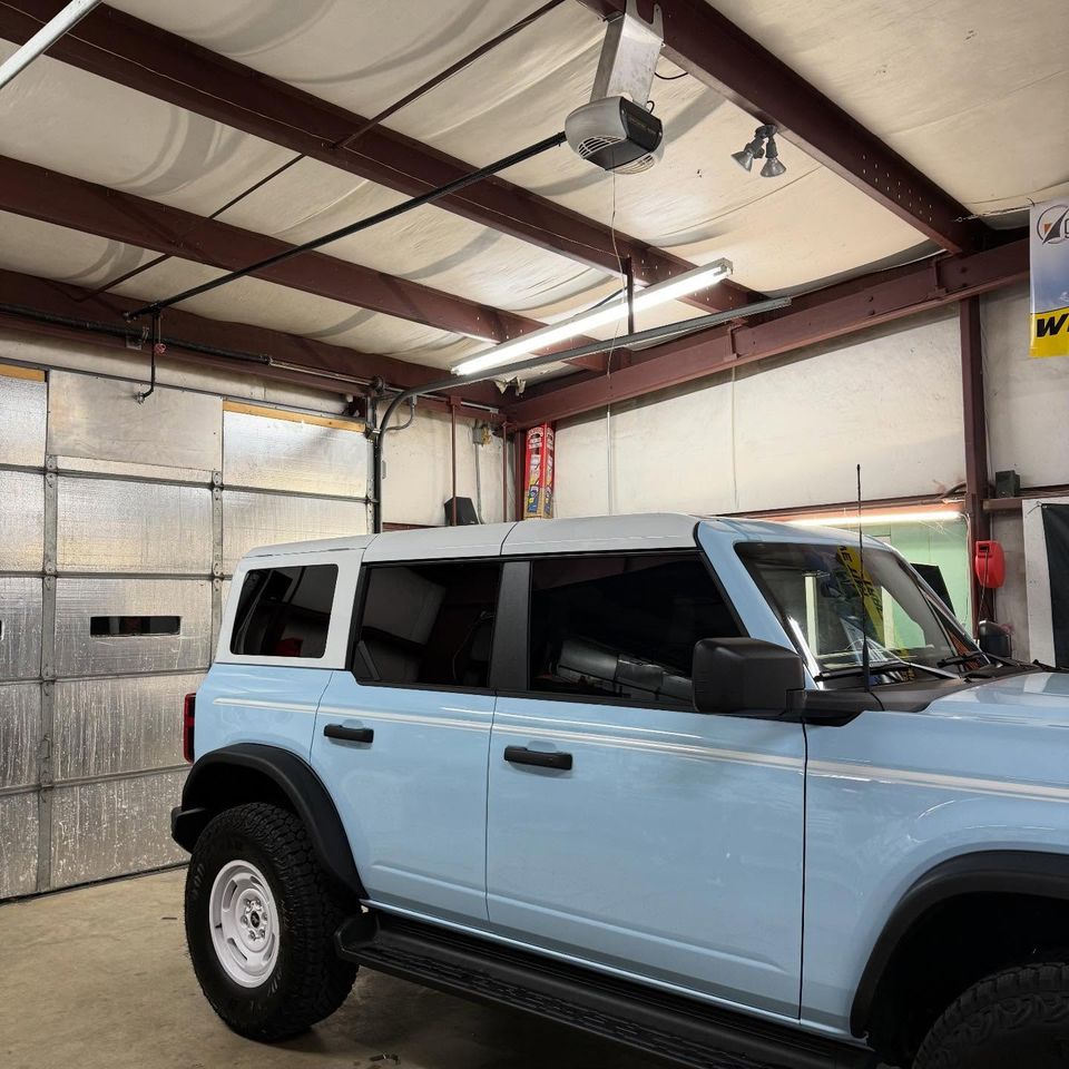 Light blue Ford Bronco with tinted side and rear windows in the auto tint shop