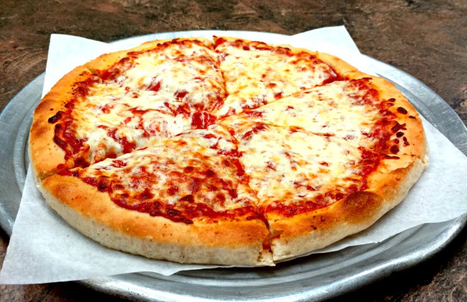 Fresh cheese pizza on a serving tray at Cocca’s Pizza.