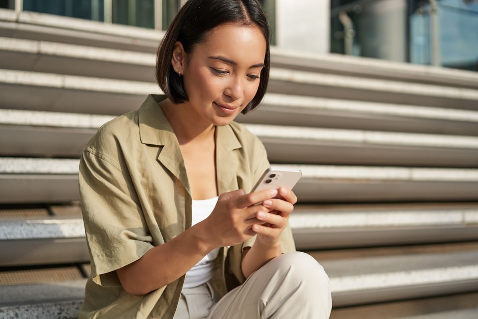 People technology smiling beautiful asian woman sitting stairs city holding mobile phone