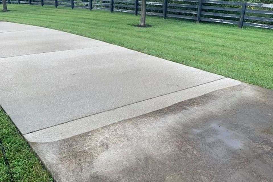 Professional driveway pressure washing in Louisville, KY showing the removal of black algae and tire marks