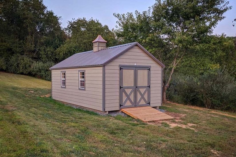 Tan cottage shed with cupola, double doors and wood ramp installed on a Knoxville TN lawn