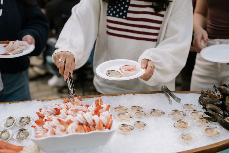 A woman picking pieces of shrimp from a raw bar, done by Shore2Shore Shucking of Long Island