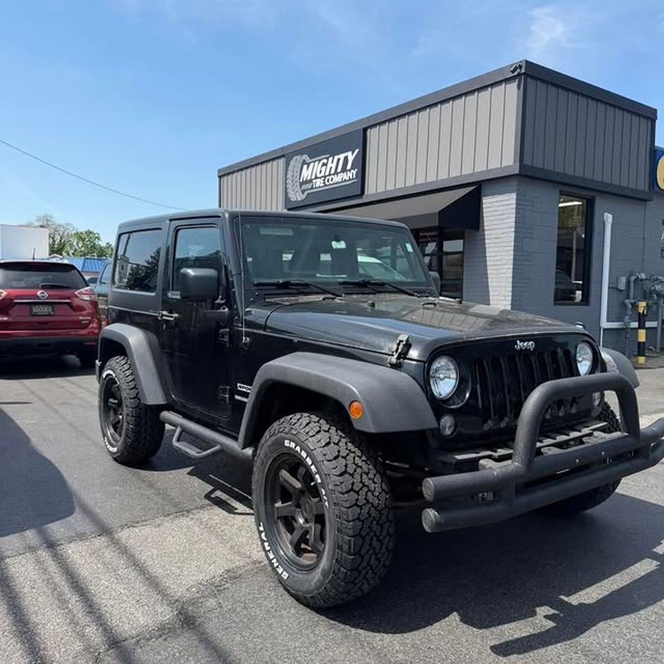 Black Jeep Wrangler parked outside Mighty Tire Company after tire installation in Claymont DE