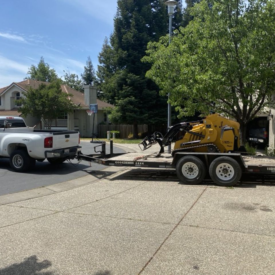 Fair Oaks Arborist truck towing trailer with compact utility loader in residential neighborhood